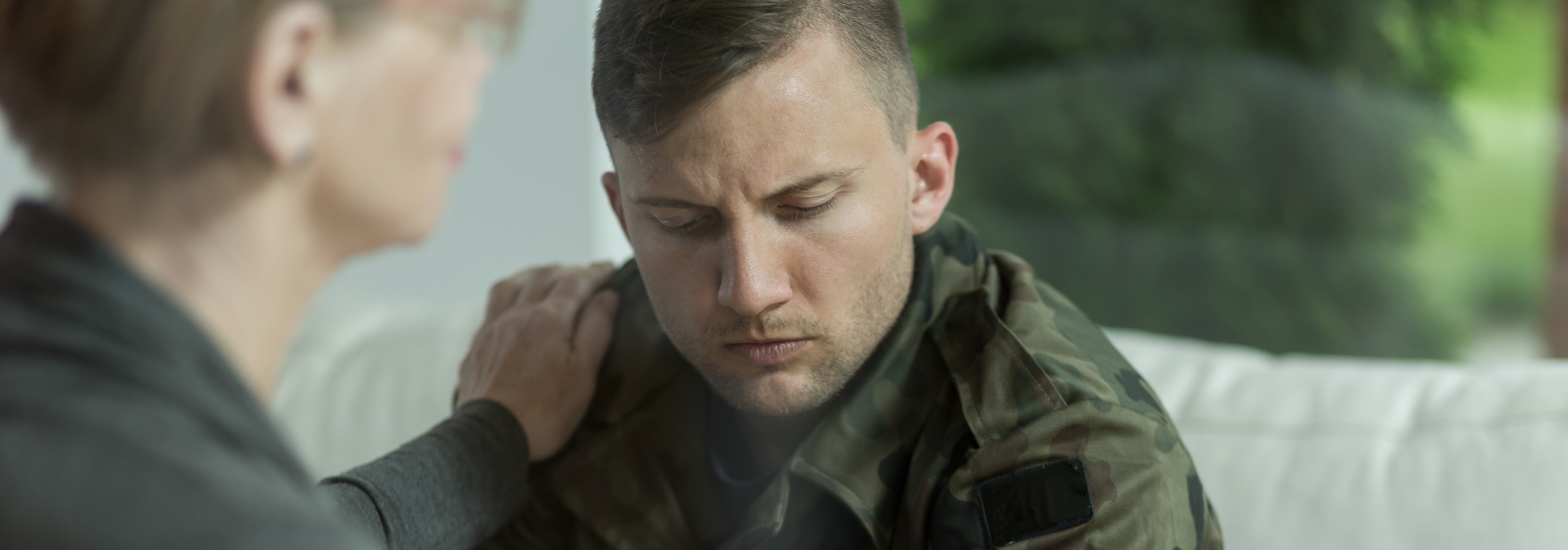 Psychologist comforting and supporting young soldier with trauma