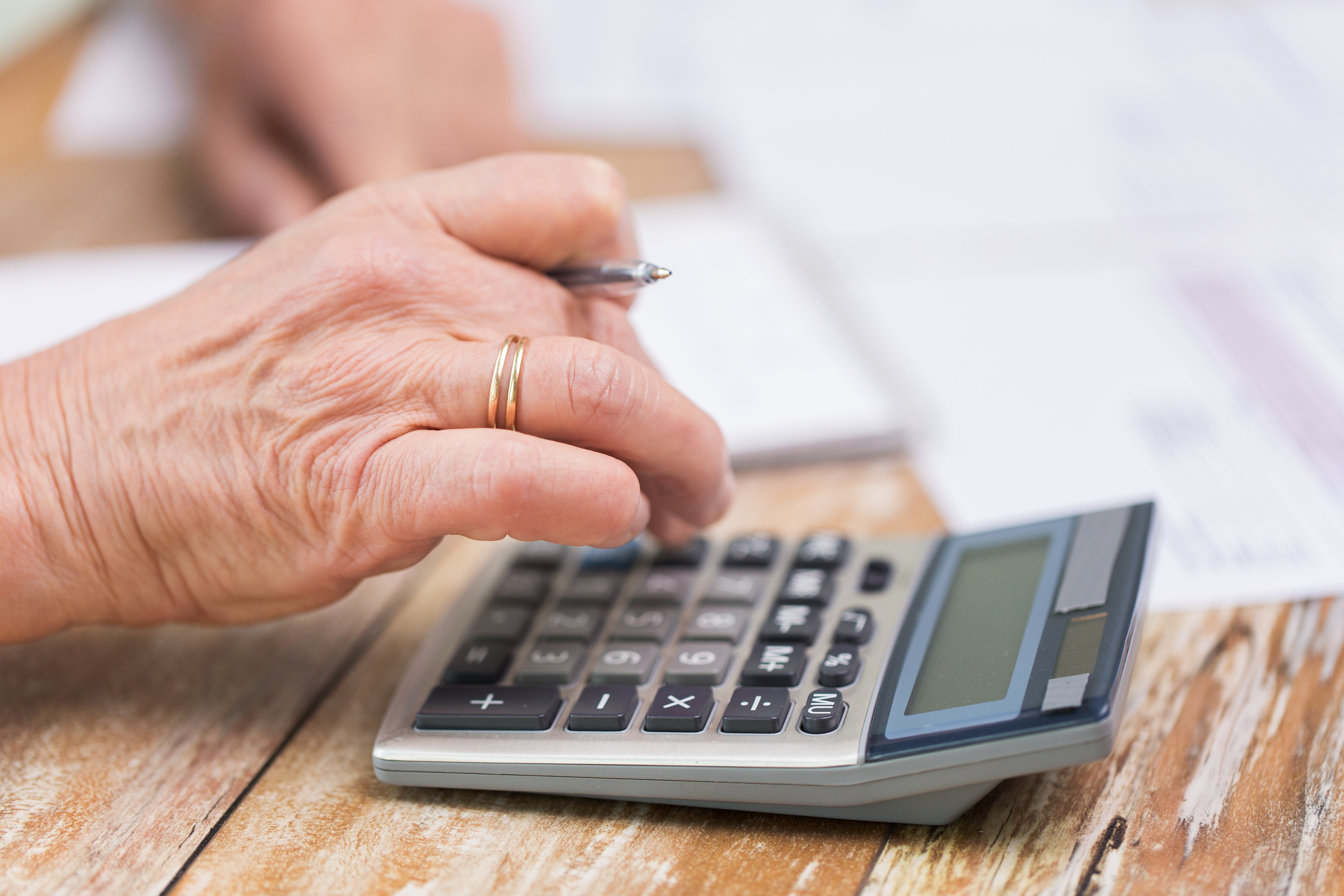 business, savings, annuity insurance, age and people concept - senior woman with calculator and papers counting at home