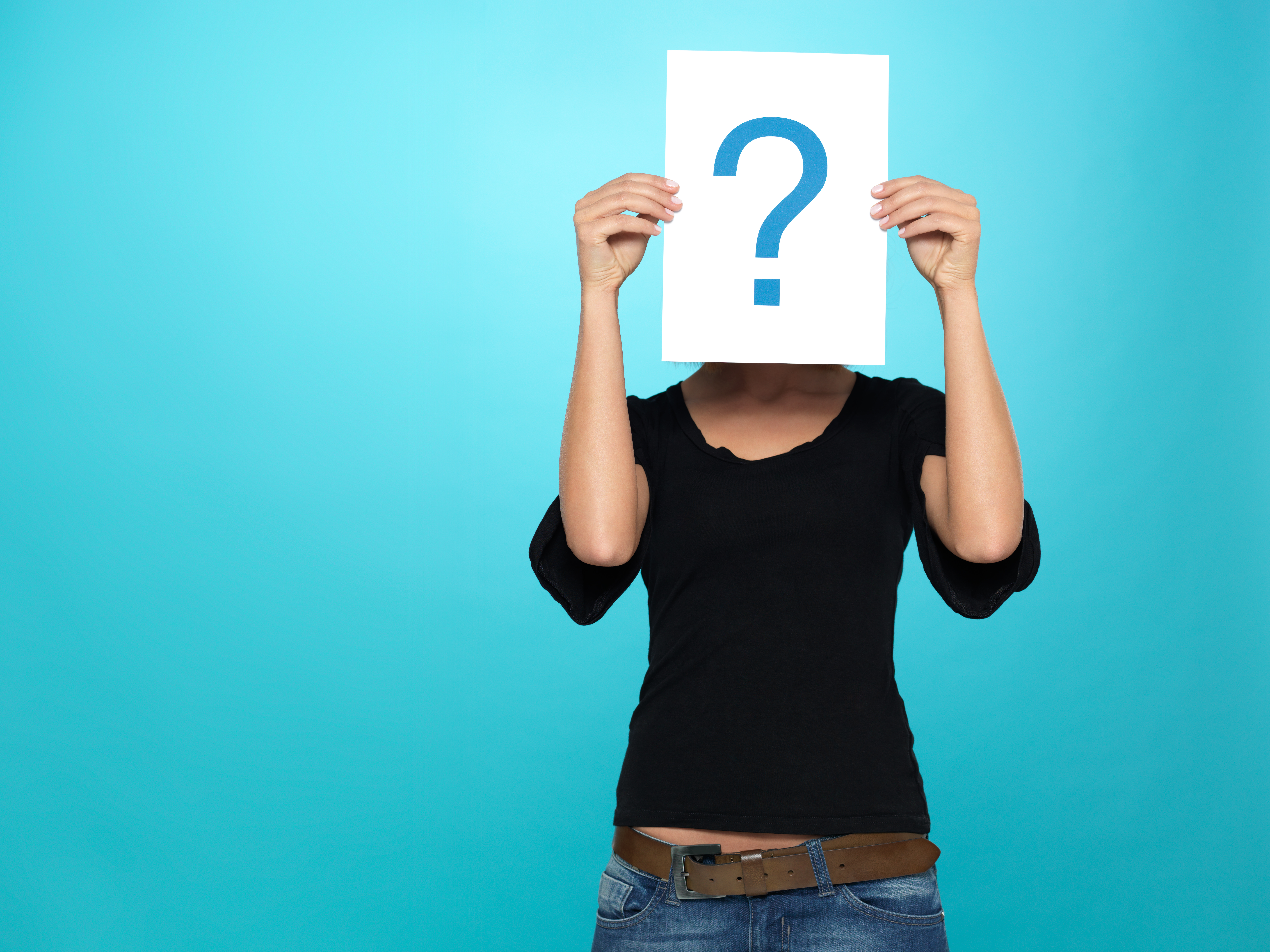 beautiful, young woman showing a question mark on a white piece of paper in front of her head, on blue background