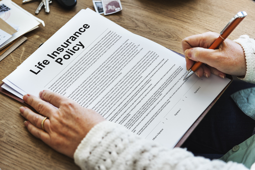 A Copy of a life insurance policy with a hand signing it