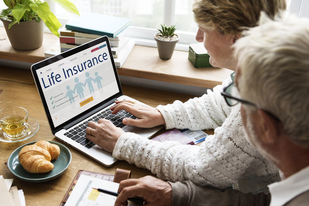 Couple researching life insurance riders on laptop